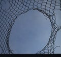 Opening in metallic net fence. isolated on blue sky background. Challenge. uncertainty. breakthrough concept. freedom concept. Royalty Free Stock Photo