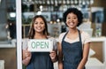 Opening a small business takes a big investment, but its worth it. Portrait of two young women holding an open sign in a