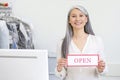 Smiling woman behind counter holding sign open