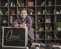 Young smiling man leather maker standing near open sign at wooden table