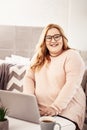 Openly laughing plus-size woman working as freelancer from home