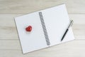 Openning note book white blank page with pen and lovely red ceramic heart shape on light grey wooden table background Royalty Free Stock Photo