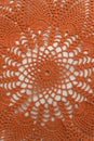Openwork napkin for decor on white background. Bright orange crocheted product. Knitted lace pattern. Vertical frame