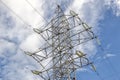 Steel pylon of the high-voltage power line against the sky and clouds