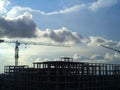 Operated heavy duty crane build a skyscrapper tower with blue sky and dark cloud as background Royalty Free Stock Photo