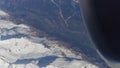Operating jet engine of the airplane, snowy montain peaks and distant alpine town