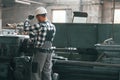 Operating machine. Factory male worker in uniform is indoors Royalty Free Stock Photo