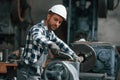 Operating machine. Factory male worker in uniform is indoors Royalty Free Stock Photo