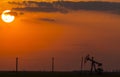 Operating oil and gas well profiled on sunset sky