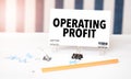 OPERATING PROFIT sign on paper on white desk with office tools. Blue and white background