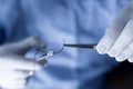 Operator holding half circle with forceps during operation. Medical professional in scrubs handling sutures.