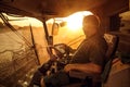 Operator inside a combine harvester at sunset