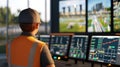 Operator monitoring multiple screens in a control room while overseeing construction activity during daytime operations Royalty Free Stock Photo