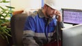 Operator in overalls answers a phone call while sitting in the control room