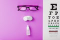 Ophthalmic accessories Glasses and lenses with vision test table for vision correction on a pink background Royalty Free Stock Photo