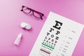 Ophthalmic accessories Glasses and lenses with vision test table for vision correction on a pink background Royalty Free Stock Photo