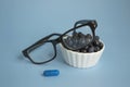 Ophthalmic concept close up. Glasses, blueberries and blueberry vitamin on a blue background. Natural products to improve and Royalty Free Stock Photo