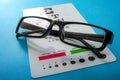 Ophthalmological exam, healthy eyes and ophthalmology concept with a pair of vision glasses and an eye chart isolated on blue Royalty Free Stock Photo
