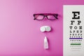 Ophthalmologist accessories glasses, lenses and vitamins with a test target for vision correction on a pink background Royalty Free Stock Photo