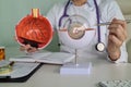 Ophthalmologist holds anatomical model of human eye and pen in hands