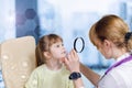 An ophthalmologist looking at small child eyes through the magnifier