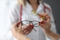 Ophthalmologist offering patient glasses for vision in clinic closeup