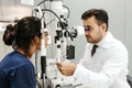 Ophthalmologist is performing a medical examination on a female patient in a laboratory setting.