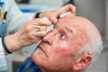 Ophthalmologist pouring drops to dilate the pupil to a man