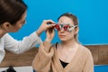 Ophthalmologist is wearing trial frame glasses on girl. Examination with ophthalmologist for selection of trial glasses
