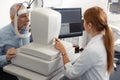 Ophthalmologist wearing white uniform sitting near laptop