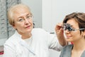 Ophthalmologist woman in white coats examining young woman eyes in clinic.