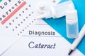 Ophthalmology diagnosis Cataract. Snellen eye chart, two bottles of eye drops medications lying on notebook with inscription