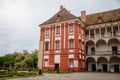 Opocno castle, renaissance chateau, courtyard with arcades and red facade, green lawn with statue and flowers in foreground, sunny Royalty Free Stock Photo