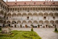 Opocno castle, renaissance chateau, courtyard with arcades and red facade, green lawn with statue and flowers in foreground, sunny Royalty Free Stock Photo