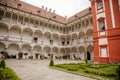 Opocno castle, renaissance chateau, courtyard with arcades and red facade, green lawn with statue and flowers in foreground, sunny Royalty Free Stock Photo