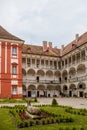 Opocno castle, renaissance chateau, courtyard with arcades and red facade, green lawn with statue and flowers in foreground, sunny Royalty Free Stock Photo