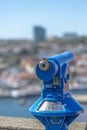 Detailed view of a public blue monocle, blurred city and blue sky as background