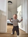 opposite the open door stands a playful child who sincerely smiles while holding a kitchen item