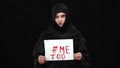 Oppressed Muslim woman in hijab holding Me too hashtag looking at camera with sad serious facial expression. Portrait of