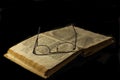 Glasses on an old book isolated on a black background