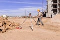 optical level is installed on construction site near pile large stones, surveyor works with satellite geodetic receiver