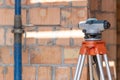 Optical level on tripod standing against brick wall Royalty Free Stock Photo