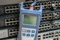 Optical Time Domain Reflectometer with wire connected to it is on the background of several switches