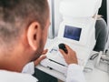 Optician checking his patient`s eye on a machine. Royalty Free Stock Photo