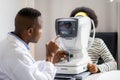 Optician Doing Optometry Eye Exam of black african american teen girl in modern clinic. Doctor and patient in ophthalmology clinic