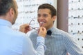 optician fitting eyeglasses on smart young man