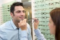 optician fitting eyeglasses to client