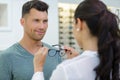 optician fitting glasses onto handsome male customer