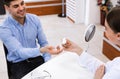 Optician giving container with contact lenses to male patient