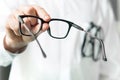 Optician giving new glasses to customer for testing and trying. Royalty Free Stock Photo